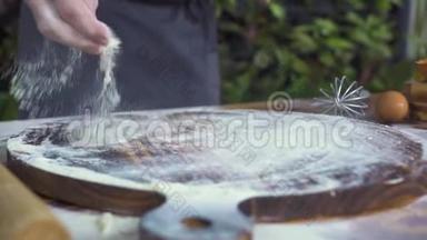 面包师把<strong>一把</strong>面粉倒在木板上，把面团揉在木桌上。 手工厨师做蛋糕面团